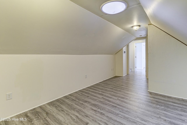 additional living space with light wood finished floors and vaulted ceiling