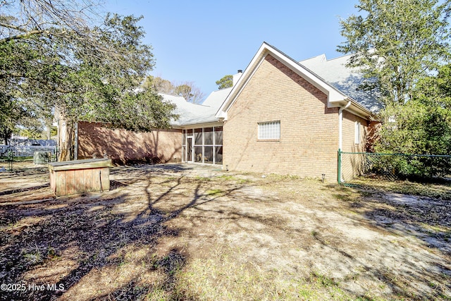 back of property featuring fence private yard, a sunroom, brick siding, and a chimney