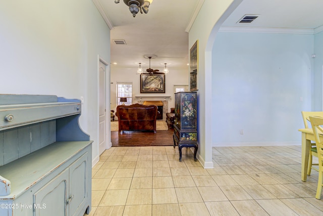 hallway featuring light tile patterned floors, ornamental molding, arched walkways, and visible vents