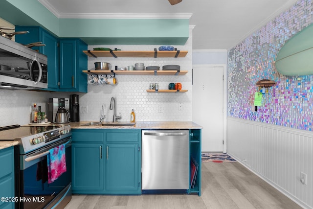 kitchen featuring stainless steel appliances, a sink, light wood-style flooring, and blue cabinetry