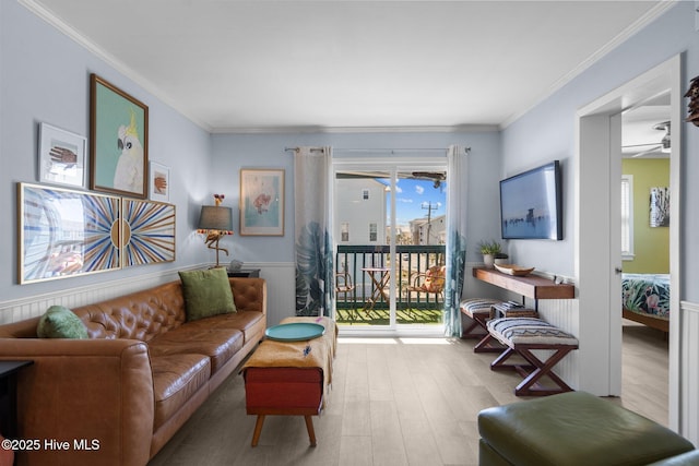 living room with a ceiling fan, wainscoting, crown molding, and wood finished floors