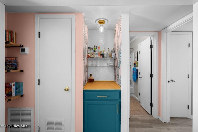 interior space with a bar, light wood finished floors, and visible vents