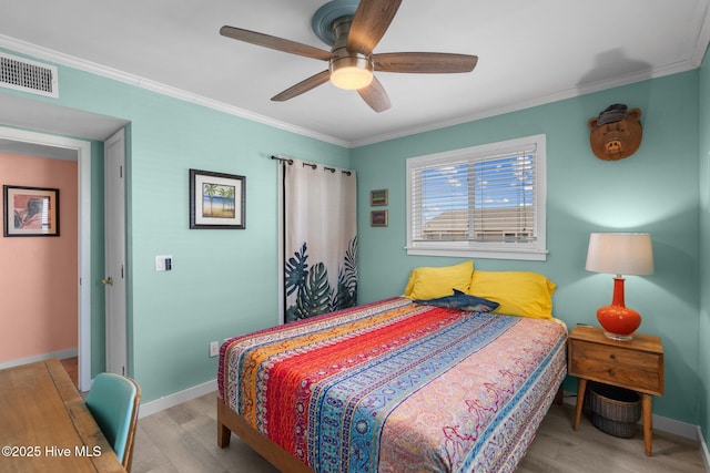 bedroom featuring ornamental molding, light wood-style flooring, visible vents, and baseboards