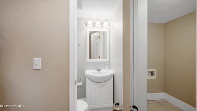 half bathroom with tile patterned flooring, toilet, visible vents, vanity, and baseboards