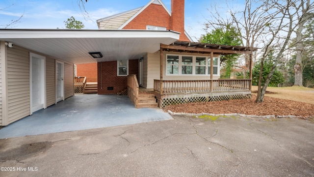 view of front facade with driveway, a carport, and brick siding