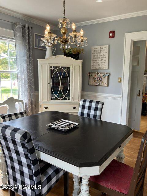 dining room with a chandelier, crown molding, and wood finished floors