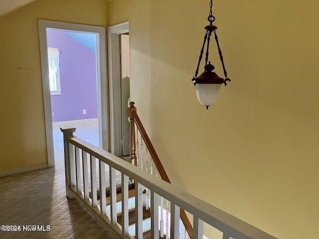 hall with baseboards, carpet flooring, and an upstairs landing