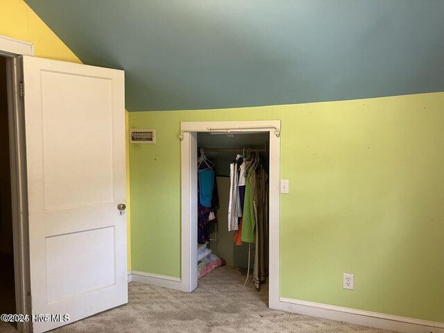 hallway with vaulted ceiling, carpet flooring, and an upstairs landing