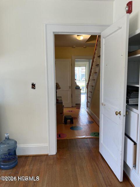 hallway featuring stairs, wood finished floors, and baseboards