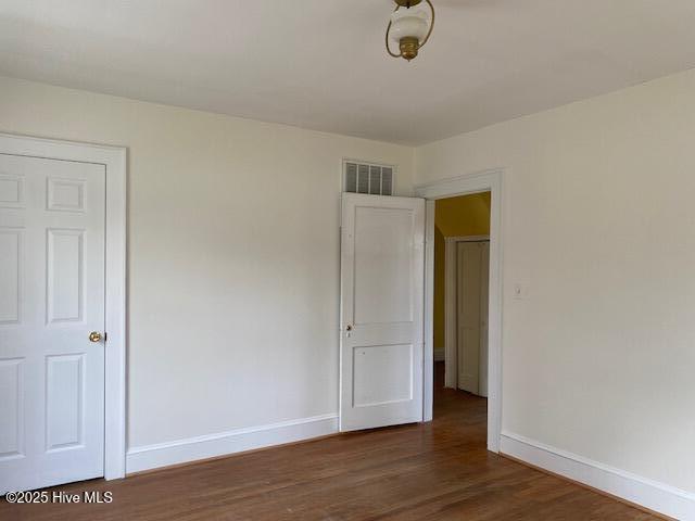 empty room with baseboards, a baseboard heating unit, and wood finished floors