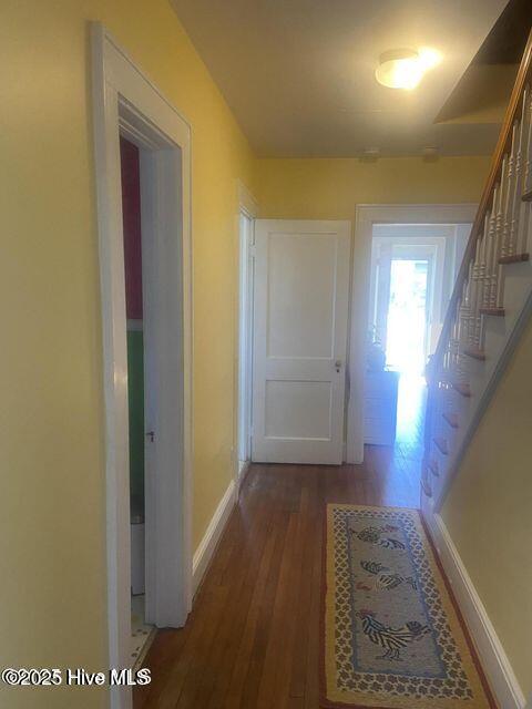 hallway with stairs, baseboards, and wood finished floors