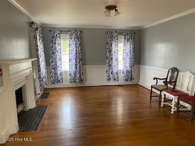 sitting room featuring ornamental molding, a fireplace, and wood finished floors