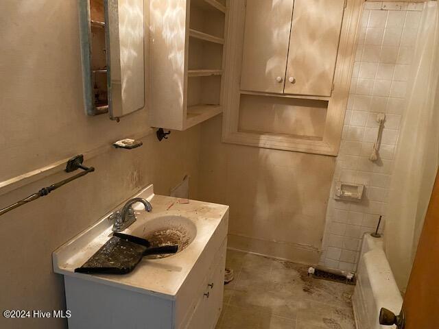 bathroom with radiator, shower / tub combination, baseboards, and vanity