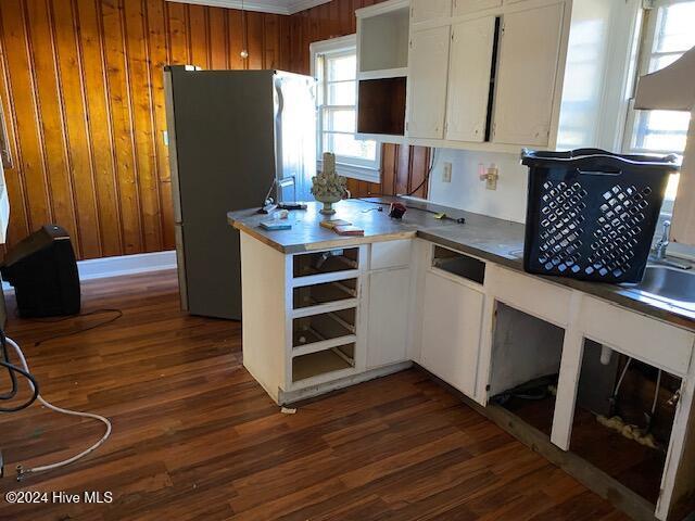 kitchen featuring wooden walls, white cabinetry, dark wood-style flooring, and freestanding refrigerator