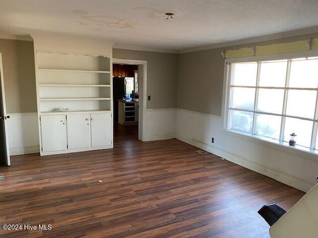 spare room with a wainscoted wall, crown molding, a textured ceiling, and dark wood-style flooring