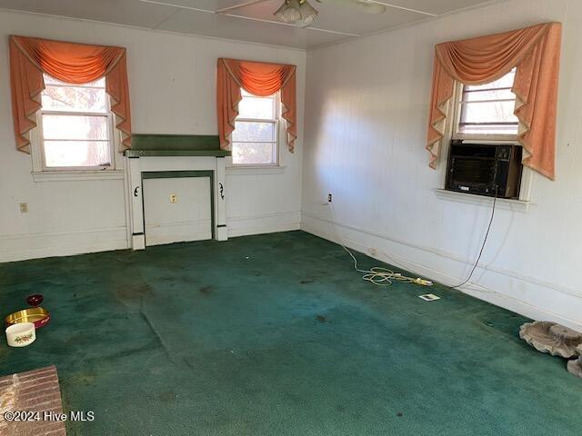 empty room with a ceiling fan, dark colored carpet, and baseboards