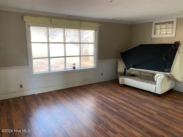 unfurnished bedroom with wainscoting, dark wood finished floors, visible vents, and crown molding