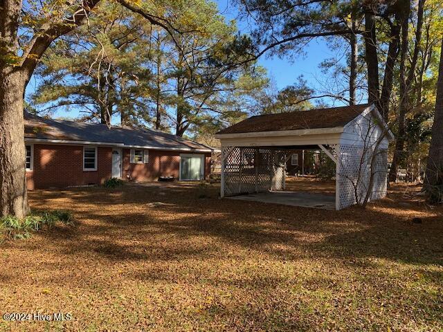 rear view of property with a lawn, a carport, and brick siding