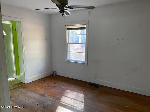 spare room featuring ceiling fan, wood finished floors, visible vents, and baseboards