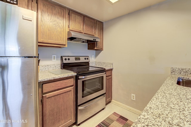 kitchen with appliances with stainless steel finishes, under cabinet range hood, and baseboards