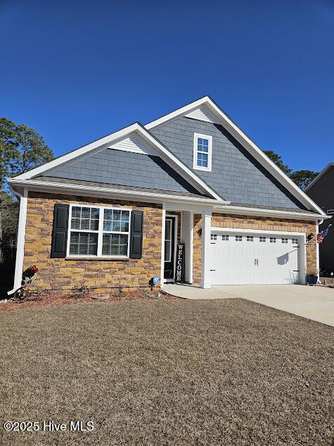 view of front of house featuring a garage, stone siding, and driveway