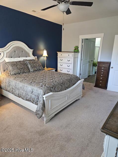 bedroom with visible vents, carpet, and a ceiling fan