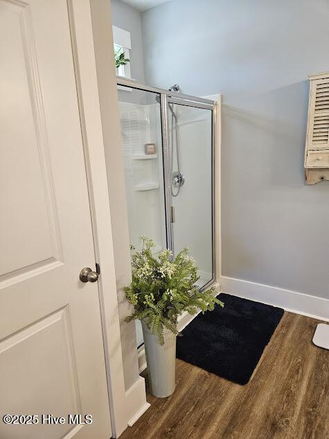 bathroom with a shower stall, baseboards, and wood finished floors