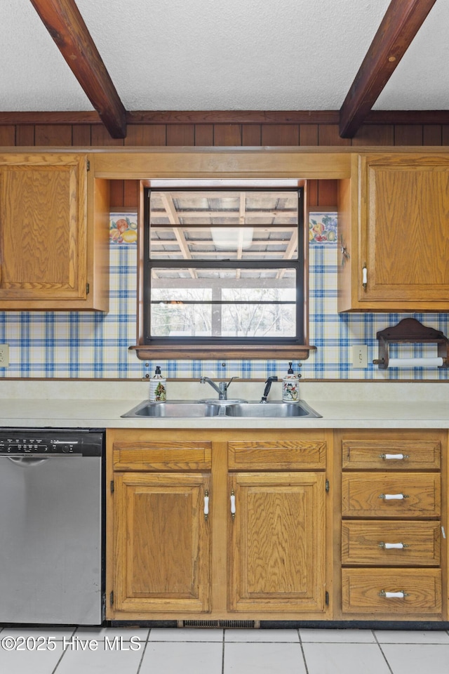 kitchen with beam ceiling, light countertops, dishwasher, and a sink