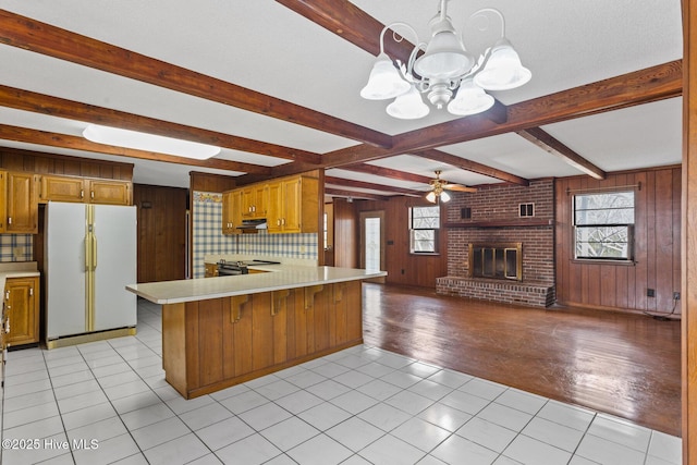 kitchen with light countertops, a wealth of natural light, a brick fireplace, and freestanding refrigerator