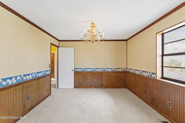 spare room featuring wooden walls, a wainscoted wall, crown molding, and a textured ceiling