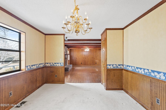 unfurnished dining area with a textured ceiling, wood walls, wainscoting, and carpet flooring