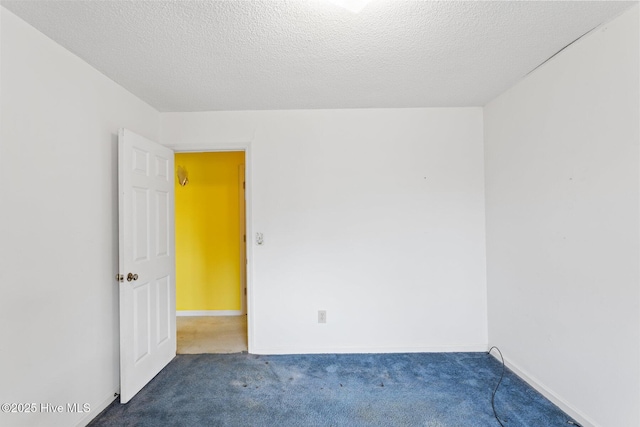 empty room with a textured ceiling, baseboards, and carpet flooring