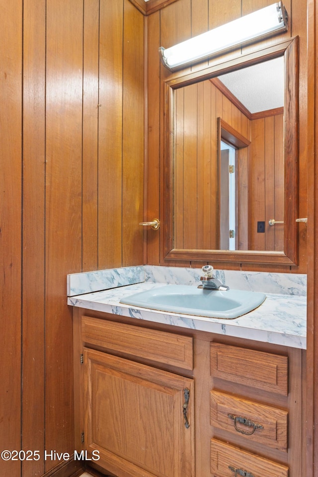 bathroom featuring crown molding, wood walls, and vanity