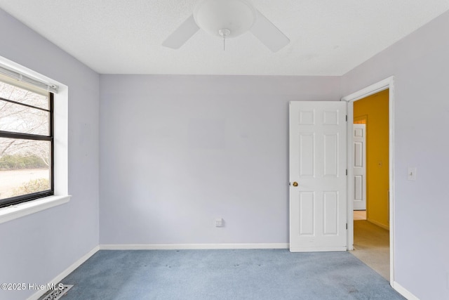 carpeted spare room with a textured ceiling, baseboards, and a ceiling fan