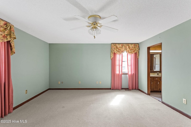 spare room featuring baseboards, a textured ceiling, a ceiling fan, and carpet flooring