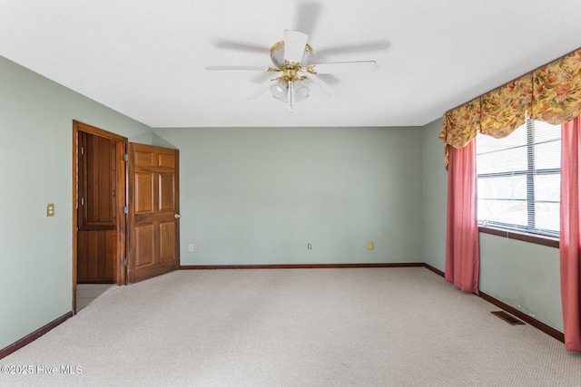 empty room with baseboards, a ceiling fan, visible vents, and light colored carpet