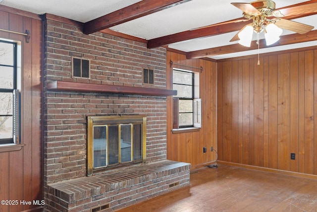 unfurnished living room featuring a fireplace, beam ceiling, and wooden walls