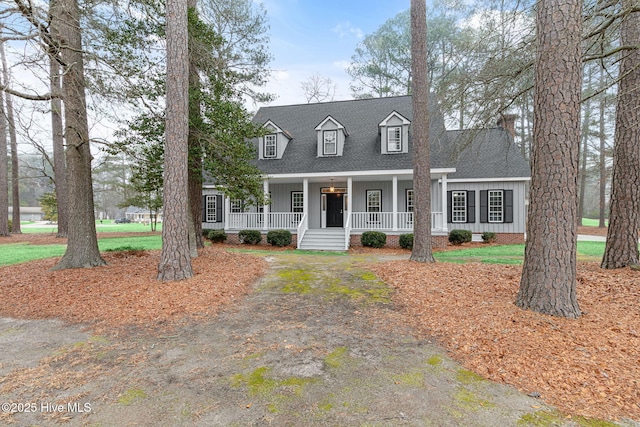 cape cod home featuring a porch, board and batten siding, and a shingled roof