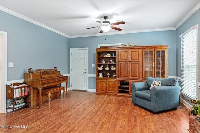 sitting room featuring light wood-style floors, baseboards, ceiling fan, and crown molding