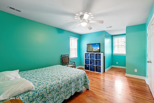 bedroom featuring a ceiling fan, baseboards, visible vents, and wood finished floors