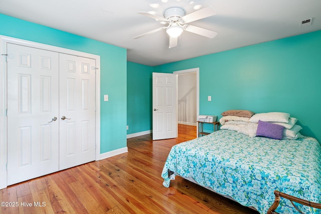 bedroom with baseboards, a closet, wood finished floors, and visible vents