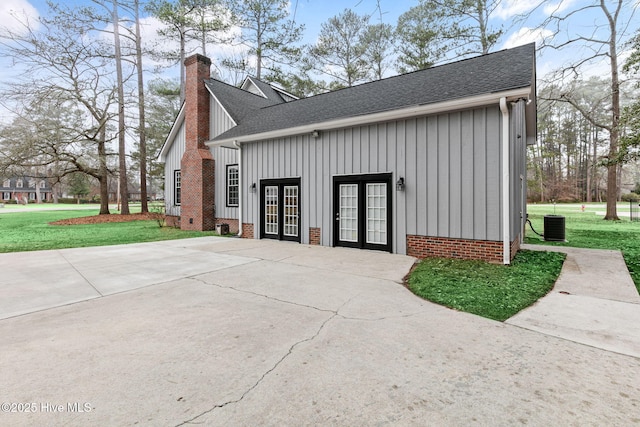 view of side of home featuring french doors, board and batten siding, a chimney, and roof with shingles