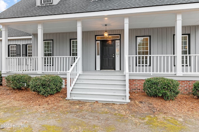 doorway to property featuring roof with shingles, covered porch, and board and batten siding