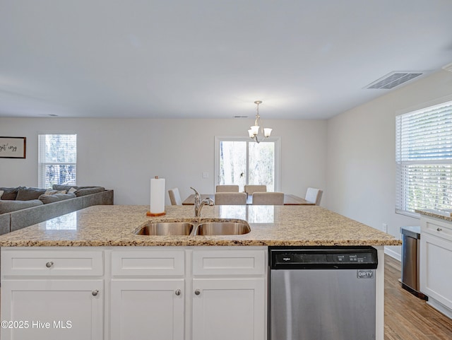 kitchen featuring light stone counters, light wood-style flooring, a sink, visible vents, and dishwasher