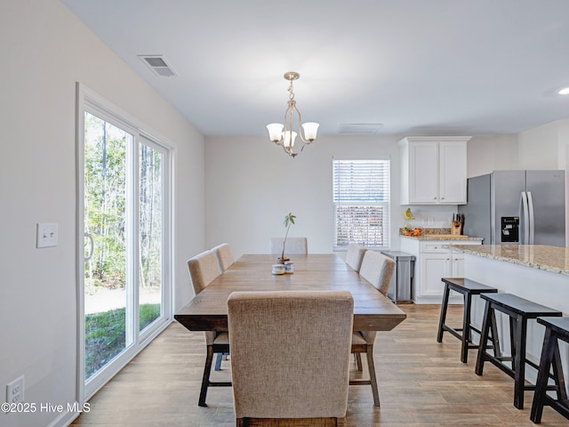 dining room with light wood-style floors, visible vents, and an inviting chandelier