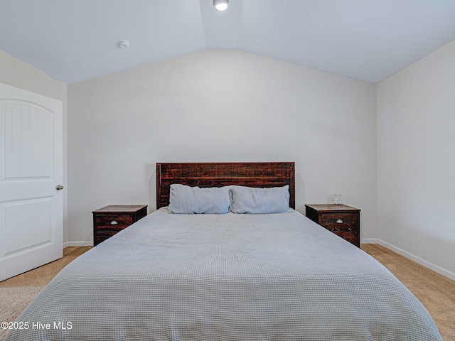 bedroom featuring lofted ceiling, baseboards, and carpet flooring