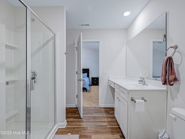 ensuite bathroom featuring vanity, wood finished floors, visible vents, and a shower stall