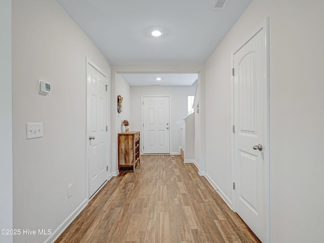 corridor featuring visible vents, baseboards, and wood finished floors