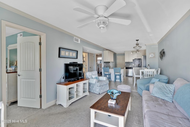 living area featuring ceiling fan, light carpet, visible vents, baseboards, and ornamental molding