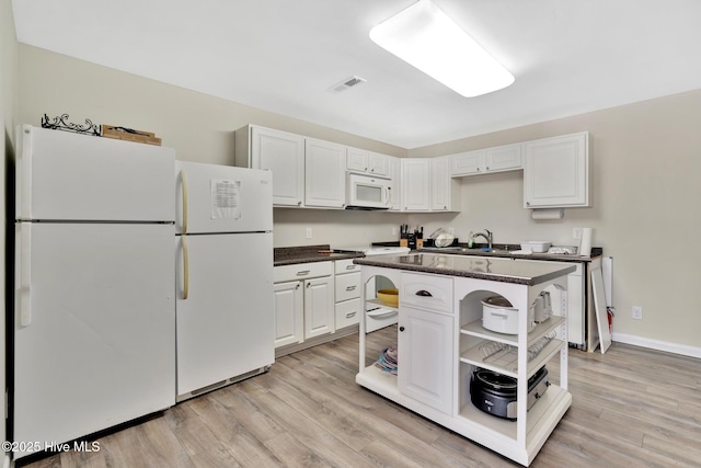 kitchen with a center island, open shelves, dark countertops, white cabinets, and white appliances